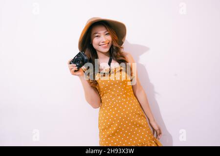 ritratto di sorridente ragazza in cappello con macchina fotografica posa isolata su sfondo pastello Foto Stock