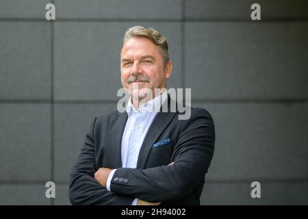 Uomo elegante e sicuro di mezza età in un abito in piedi con braccia ripiegate che guardano la fotocamera Foto Stock