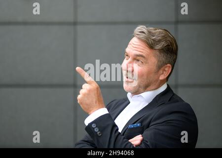 Ritratto della parte superiore del corpo di uomo d'affari fiducioso di mezza età sorridente e che punta con il dito verso il lato Foto Stock