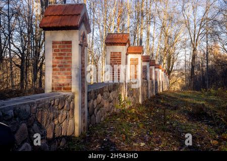 Recinzione intorno al parco costruire da mattoni e pietre, parte del maniero residenziale a Traku Voke. Architettura storicista con elementi neogotici Foto Stock