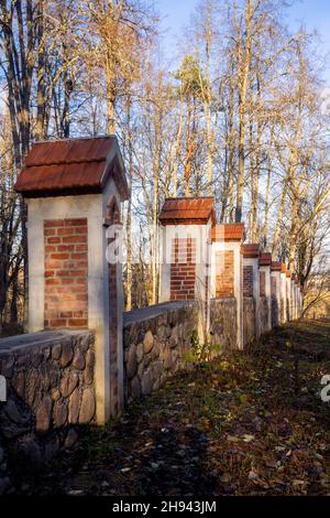 Recinzione intorno al parco costruire da mattoni e pietre, parte del maniero residenziale a Traku Voke. Architettura storicista con elementi neogotici Foto Stock