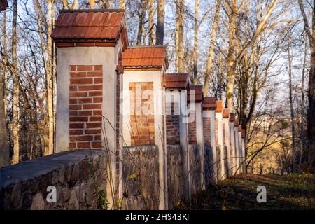 Recinzione intorno al parco costruire da mattoni e pietre, parte del maniero residenziale a Traku Voke. Architettura storicista con elementi neogotici Foto Stock