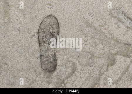 Impronta dalla suola di una scarpa da uomo contro la sabbia. Foto Stock