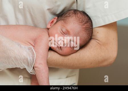 Vista ravvicinata di un medico che tiene in braccio un neonato. Foto Stock