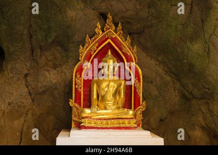 PHETCHABURI, THAILANDIA - 13 DICEMBRE 2018: Una delle tante sculture del Buddha sullo sfondo di un muro di pietra. Grotta tempio di Wat Tham KH Foto Stock