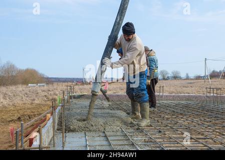 REGIONE DI LENINGRAD, RUSSIA - 28 MARZO 2021: I lavoratori dei costruttori e dei migranti stanno gettando le basi per la costruzione di un casolare di campagna Foto Stock