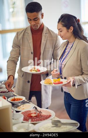 sorridenti colleghi multietnici che pranzano presso la caffetteria dell'ufficio Foto Stock