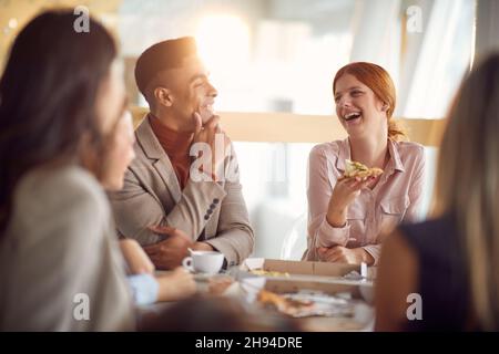 Gruppo di giovani uomini d'affari sta avendo un buon tempo in un'atmosfera amichevole durante una pausa pranzo al lavoro. Aziende, persone, aziende Foto Stock