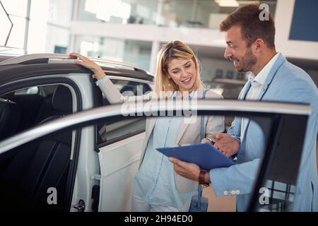 Donna d'affari di successo che acquista una nuova auto nel negozio Foto Stock