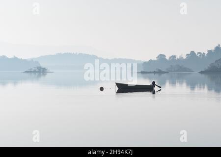 Barca da pesca sul pico nebboso all'alba - Loch Lomond, Scozia, Regno Unito Foto Stock