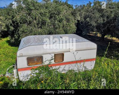 Carovana bianca abbandonata circondata dal verde in campagna in una giornata di sole Foto Stock