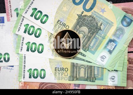 Ethereum moneta fisica che si stesa su 100 euro fatture. Foto Stock