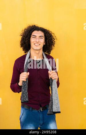 Un colpo a media distanza di un giovane ragazzo sorridente di Latino con sfondo giallo. Foto Stock