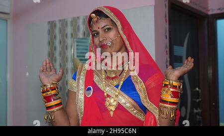 Sorridente giovane asiatica in costume tradizionale. Donna in abito rosso con gioielli d'oro. Foto Stock