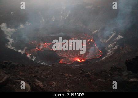 Kapoho, Stati Uniti d'America. 23 Ottobre 2021. La lava scorre dalla bocca occidentale nel cratere e nel lago di lava all'interno di Halemaumau, alla cima di Kilauea all'interno del Parco Nazionale dei Vulcani delle Hawaii, 23 ottobre 2021 a Kapok, Hawaii. La fondazione della lava in più punti di fessura sulla base e la parete ovest del cratere continuò, e un lago di lava sta crescendo all'interno del cratere vulcanico. Credit: Katie Mulliken/USGS/Alamy Live News Foto Stock