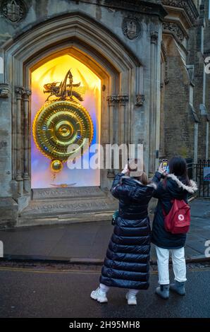 Due studenti stranieri cinesi scattano foto al tramonto del Corpus Clock al Corpus Christi College, Cambridge University, a Cambridge, Regno Unito. Foto Stock