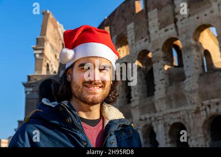 Bell'uomo che viaggia a Roma. Il giovane indossa il cappello di Babbo Natale e sorride alla macchina fotografica. Foto Stock