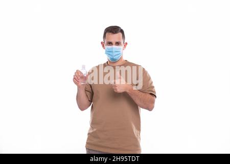 Uomo che tiene le mani igienizzatore indossare maschera medica isolato Foto Stock