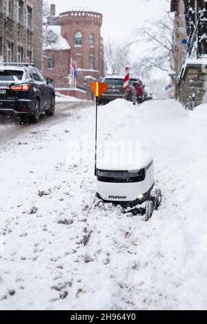 Tallinn, Estonia - 4 dicembre 2021: Veicolo drone autonomo Starship Technologies bloccato nella neve in inverno. Robot di erogazione senza contatto ad azionamento automatico. Foto Stock