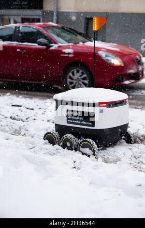 Tallinn, Estonia - 4 dicembre 2021: Veicolo drone autonomo Starship Technologies bloccato nella neve in inverno. Robot di erogazione senza contatto ad azionamento automatico. Foto Stock