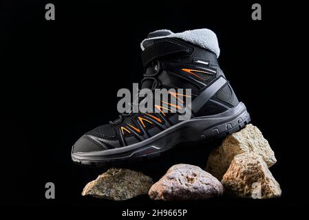 Stivali neri su sfondo scuro. Scarpe eleganti per escursioni su pietre Foto Stock