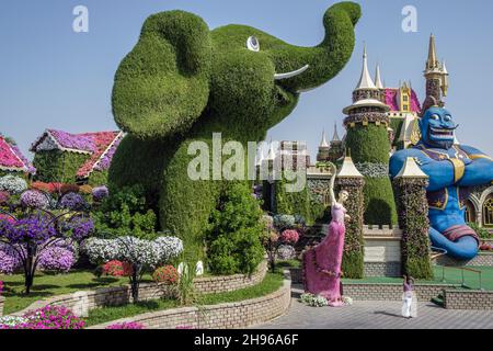 Un visitatore si pone per una fotografia di fronte all'elefante gigante al Dubai Miracle Garden Foto Stock