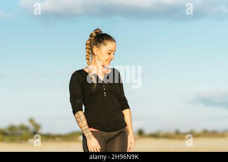 Donna bionda distratta in abbigliamento sportivo su una spiaggia durante l'alba Foto Stock