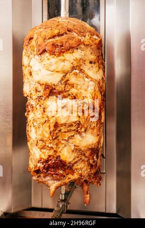 Meccanismo per tostare carne per shawarma. Pezzi di carne stoppati su spiedini di metallo per rifinire e fare l'asino. Verticale Foto Stock