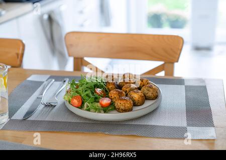 Polpette di verdure vegane sul piatto con insalata fresca su tavolo da cucina in legno. Pranzo vegetariano. Pianta cibo basato. Concetto di cibo sano. Selettivo per Foto Stock