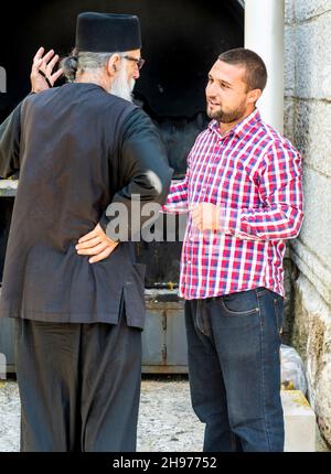 Danilovgrad comune, Montenegro-13 settembre 2019: In una chiesa sotto il monastero di Ostrog un monaco in tradizionale abito ortodosso, chiacchiera con Foto Stock