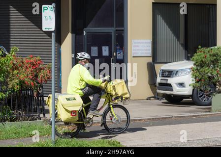 Un postman dell'Australia Post su una e-bike che consegna lettere nella periferia di Sydney, nuovo Galles del Sud, Australia Foto Stock