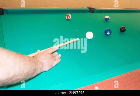 Un primo piano di un tavolo da biliardo con palle che puntano le mani dell'atleta prima di colpire. Foto Stock