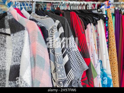 Vestiti appesi su una rotaia in un mercato di strada all'aperto. Vestiti colorati in vendita da un venditore di strada Foto Stock