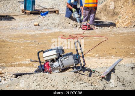 Generatore elettrico portatile sulla strada per l'alimentazione dell'utensile elettrico. Fornire corrente elettrica per il martello pneumatico. Foto Stock