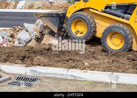 La minipala o la bobina lavorano in lavori di costruzione su strada Foto Stock