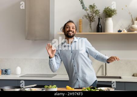 Felice uomo afroamericano danzare, cucinare cibo. Foto Stock