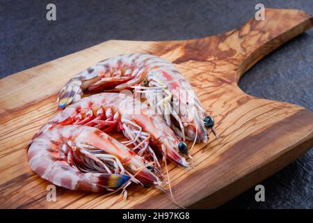 Gamberi crudi su tagliere di legno Foto Stock