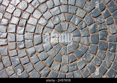 Antiche pietre di pavimentazione disposte a forma di circonferenza, lungo il raggio della texture. Al centro si trova un cerchio Foto Stock