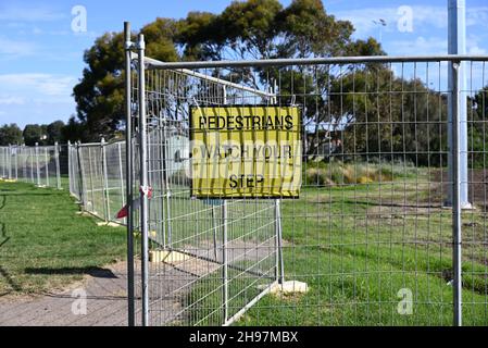 Un pedone giallo guarda il tuo segno passo, con testo nero, attaccato a una recinzione in metallo in un parco Foto Stock