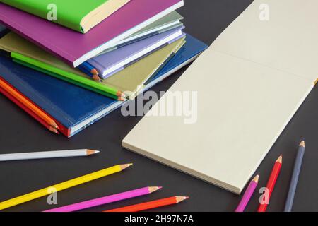 Concetto scolastico. Pila di libri, matite colorate colorate e album di schizzo aperto su sfondo di carta scuro. Spazio libero per testo o foto Foto Stock