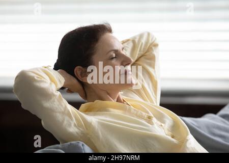 Calma rilassata donna matura respirando aria fresca a casa Foto Stock