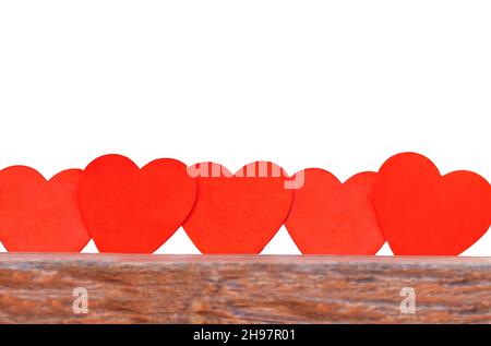 recinzione fatta da cuori isolano. cuori rossi stanno in una fila su una superficie di legno su uno sfondo povero Foto Stock