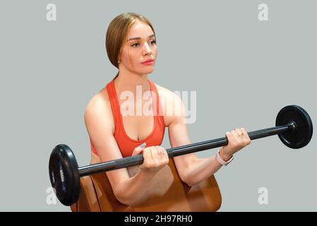 Primo piano di giovane donna in forma che fa esercizi di barbell in palestra. Concetto di stile di vita sano Foto Stock