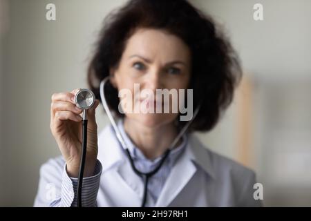 Maturo medico GP femmina mano che tiene stetoscopio primo piano oggetto Foto Stock