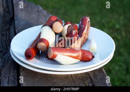 Salsicce per un pic-nic su un piatto bianco all'aperto Foto Stock