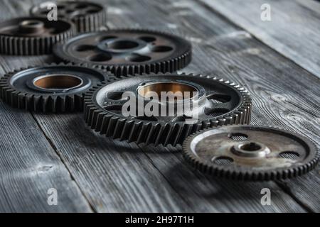 Ingranaggi e ruote in primo piano su tavola di riunione in legno, concetto di cooperazione di gestione aziendale Foto Stock