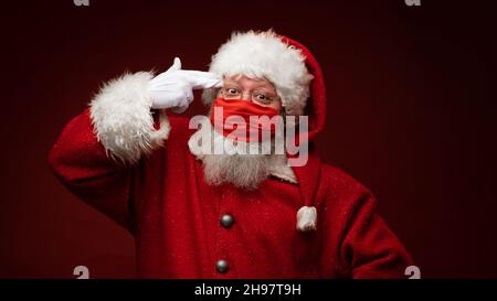 Babbo Natale suicidio con pistola immaginaria stanca di indossare maschera protettiva. Natale a distanza sociale. Covid-19 Foto Stock