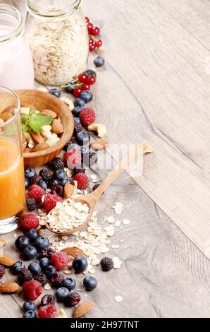 Avena con frutti di bosco, succo d'arancia e yogurt su tavola di legno Foto Stock