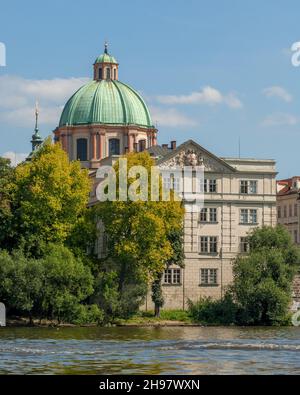 La cupola verde alta 40 metri e la cupola della neoclassica Chiesa di San Francesco d'Assisi di Jean-Baptiste Mathey si affacciano sul fiume Moldava di Praga. Foto Stock