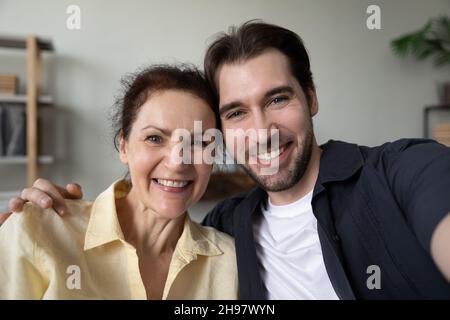 Figlio adulto felice e mamma matura che abbraccia con amore Foto Stock